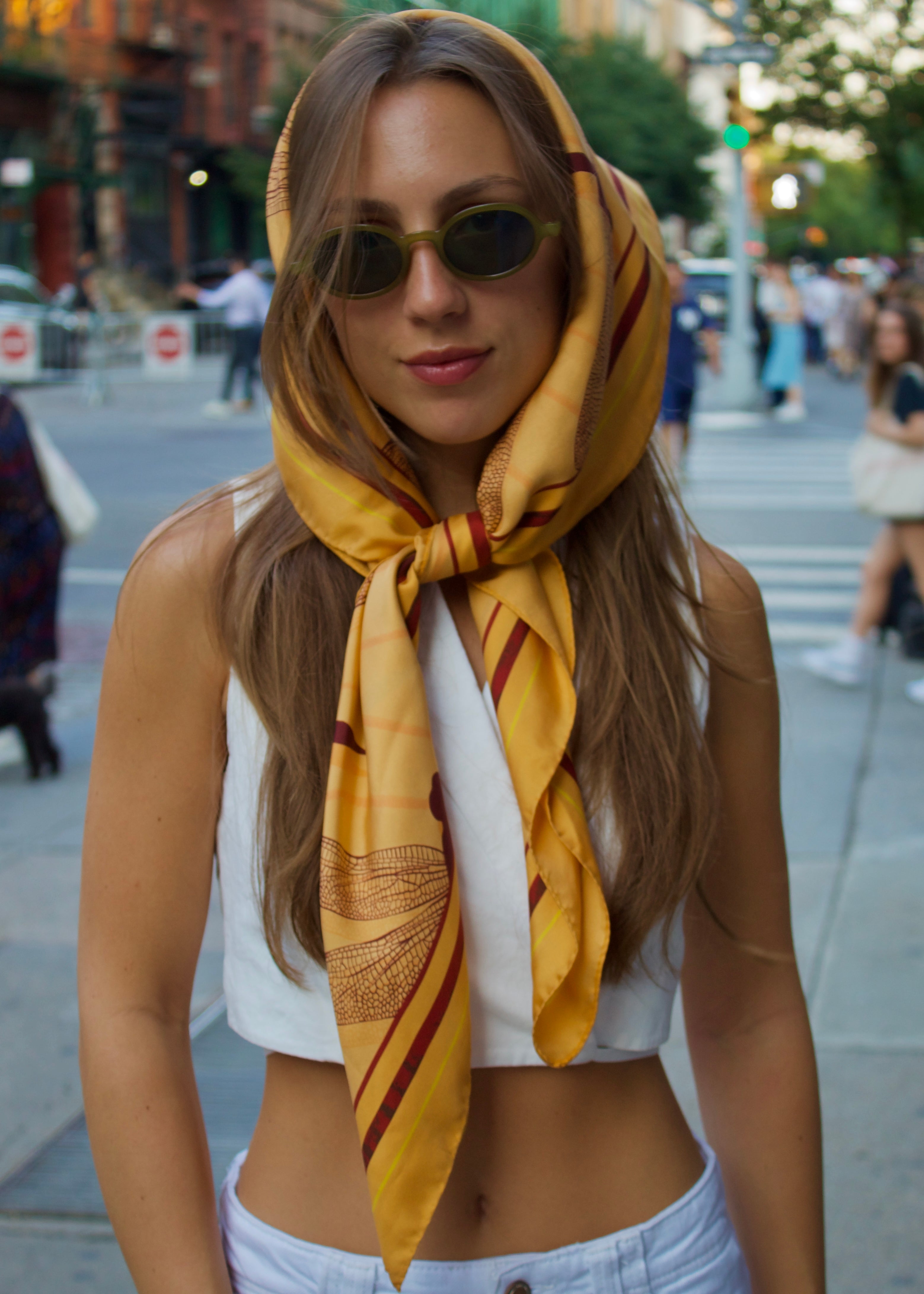 Woman styling the TAMARA signature silk scarf over her hair with sunglasses in New York City — chic and confident silk scarf look with cool NYC style.